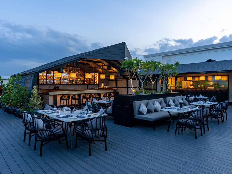 Expansive view of The Residency Towers Puducherry's elegant rooftop dining, showcasing tables and the serene sky.