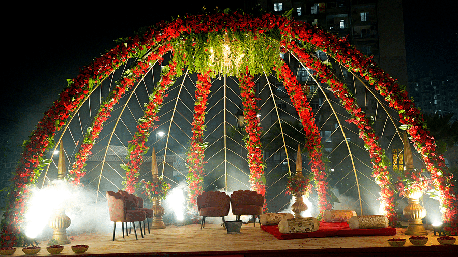An outdoor stage or archway at The Gaurs Sarovar Premiere, heavily decorated with flowers and lights, prepared for a wedding or special event at night.