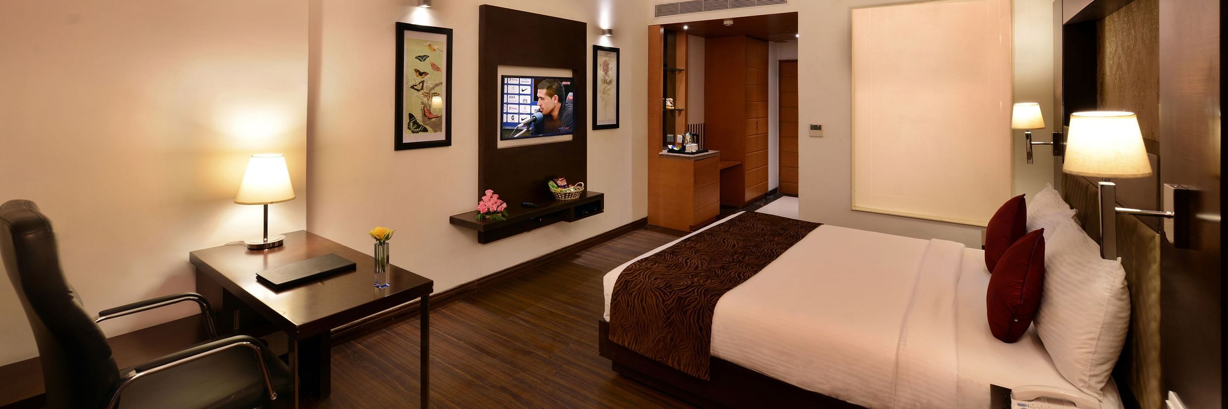 Image of executive suites with a large bed, TV, chair and a table