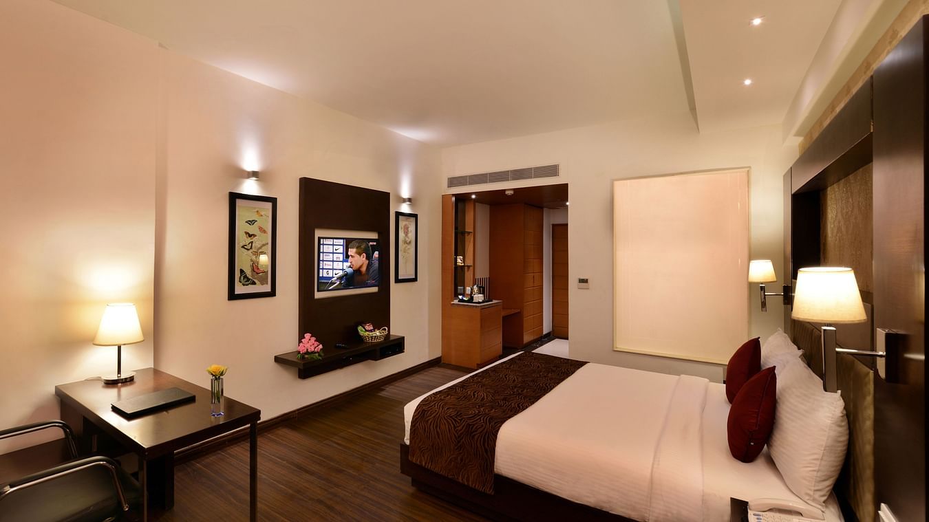 Image of executive suites with a large bed, TV, chair and a table