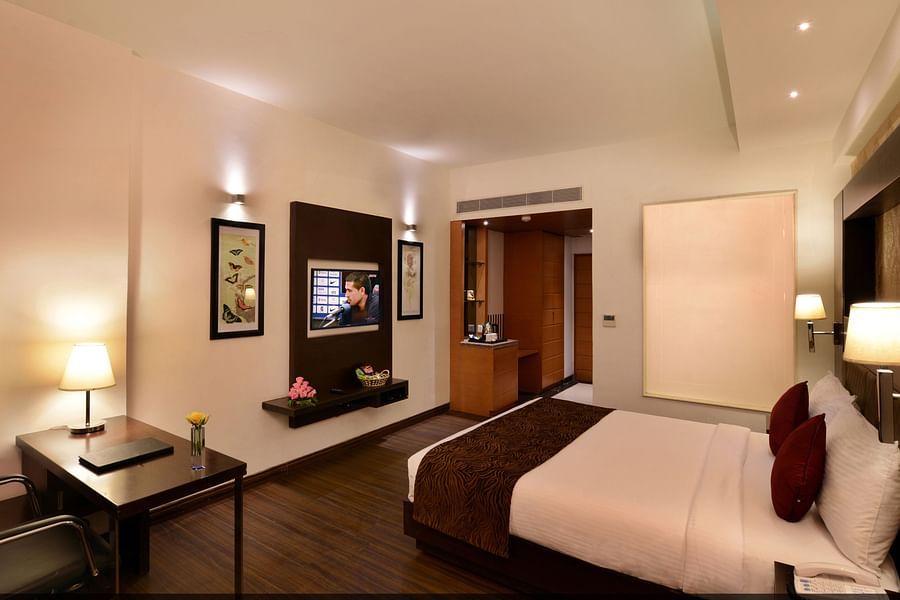 Image of executive suites with a large bed, TV, chair and a table