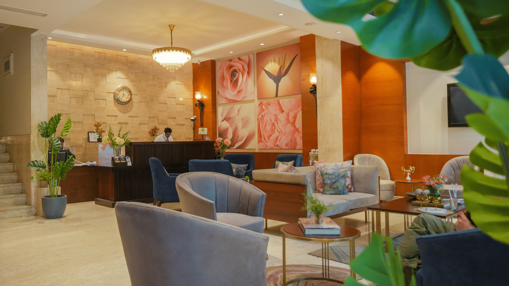 Elegant hotel lobby with warm lighting, modern grey armchairs, wooden wall panels, and a reception desk with stone-textured walls