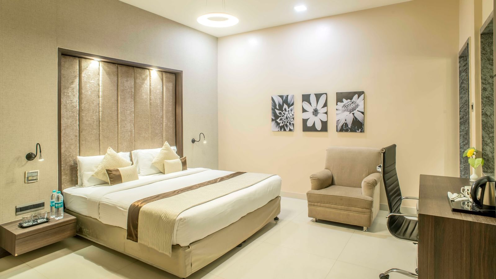 Bright hotel room with a king size bed, a sitting area, and decorative wall art | The Citi Residenci Hotel Durgapur