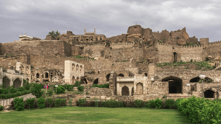 Ancient stone fort ruins with arched doorways and green lawn in the foreground under an open sky.