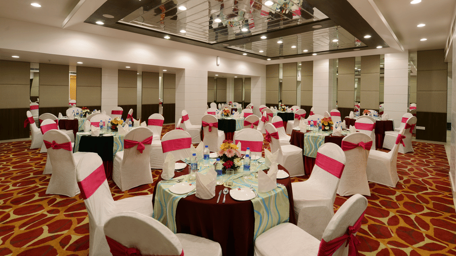 A banquet hall with chairs and tables decorated with sashes 