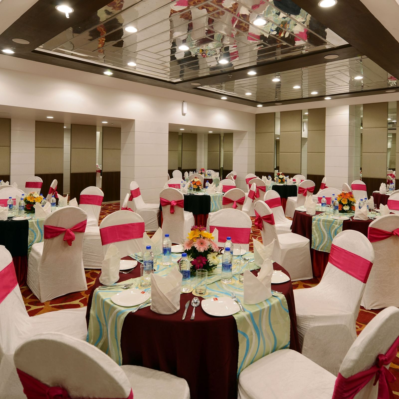 A banquet hall with chairs and tables decorated with sashes 