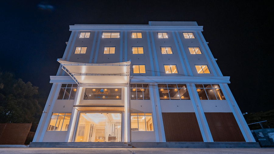 A night view of a modern multi-storey hotel building, brightly lit with warm lights emanating from the windows and entrance at Lotus Leaf Boutique Hotel.