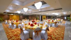 An image of the Royal Ballroom in Agra with chairs placed around round tables and chandeliers hanging from the ceiling - Golden Tulip, Agra