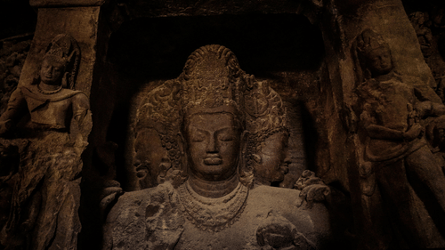 A carved stone sculpture of a deity with detailed surroundings in a cave.