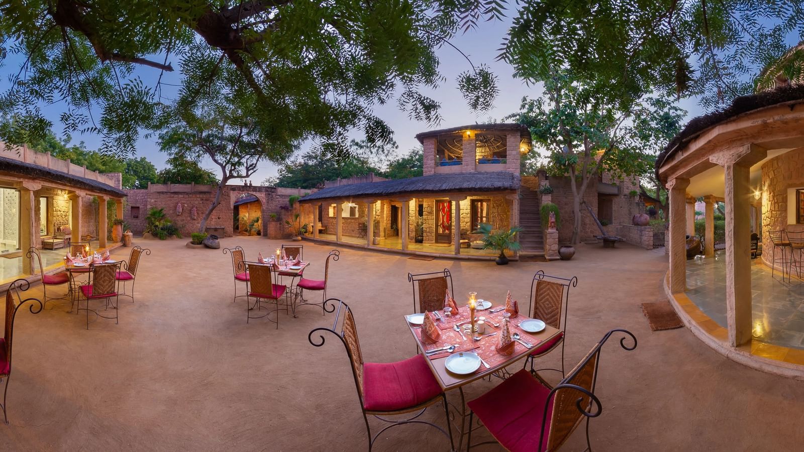 Outdoor dining space at Manvar Resort Desert and Camp featuring a sets of chairs and tables with food on them.