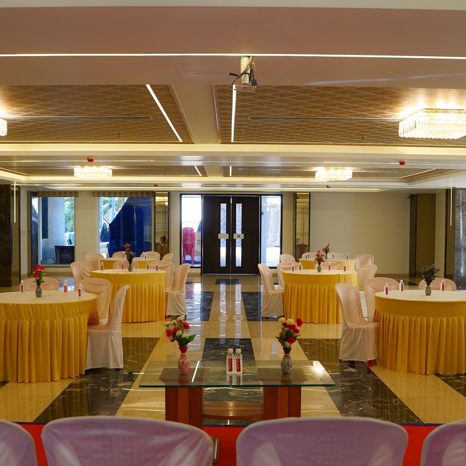 Another view of a smaller event room at BNGV Grandeur Hotel and Banquets, featuring set tables and a stage area.
