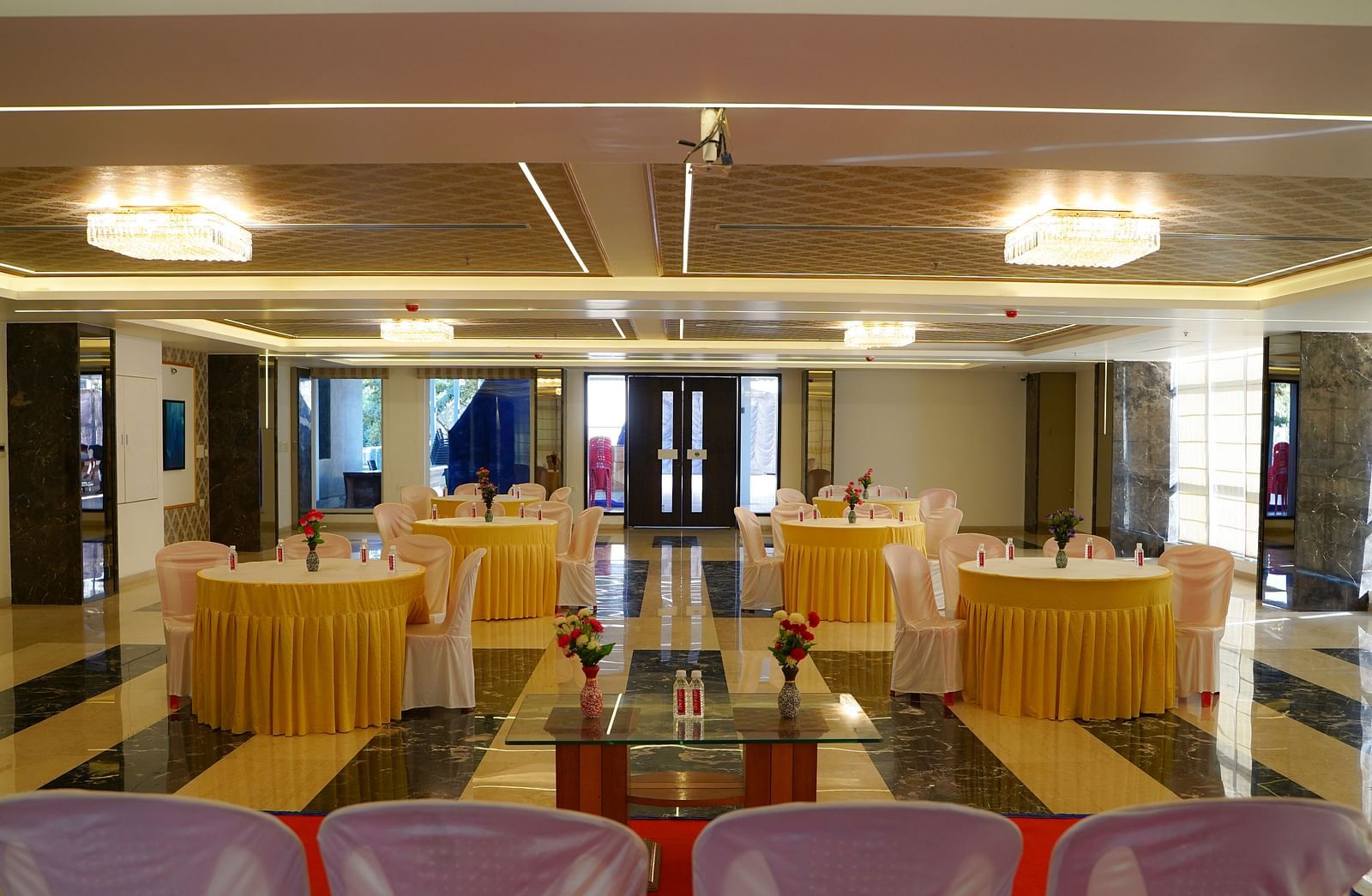 Another view of a smaller event room at BNGV Grandeur Hotel and Banquets, featuring set tables and a stage area.