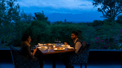 A couple enjoying a romantic meal outdoors in the evening with candlelight at The Serai Bandipur.