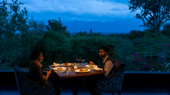 A couple enjoying a romantic meal outdoors in the evening with candlelight at The Serai Bandipur.