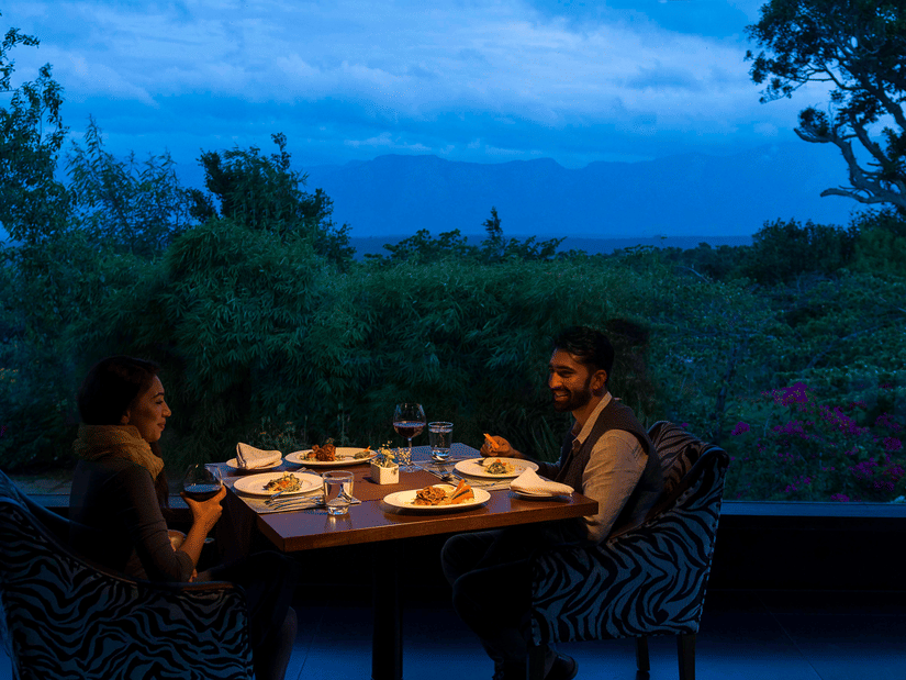 A couple enjoying a romantic meal outdoors in the evening with candlelight at The Serai Bandipur.