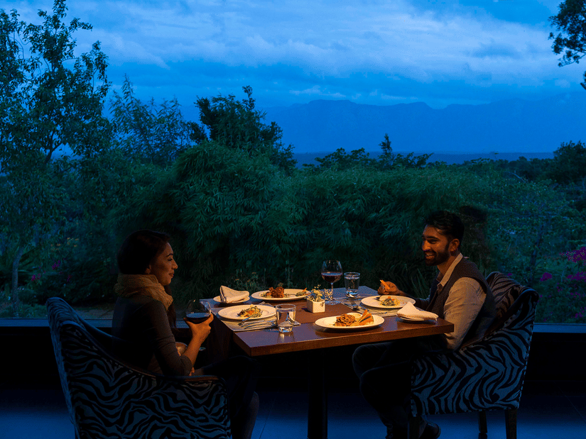 A couple enjoying a romantic meal outdoors in the evening with candlelight at The Serai Bandipur.