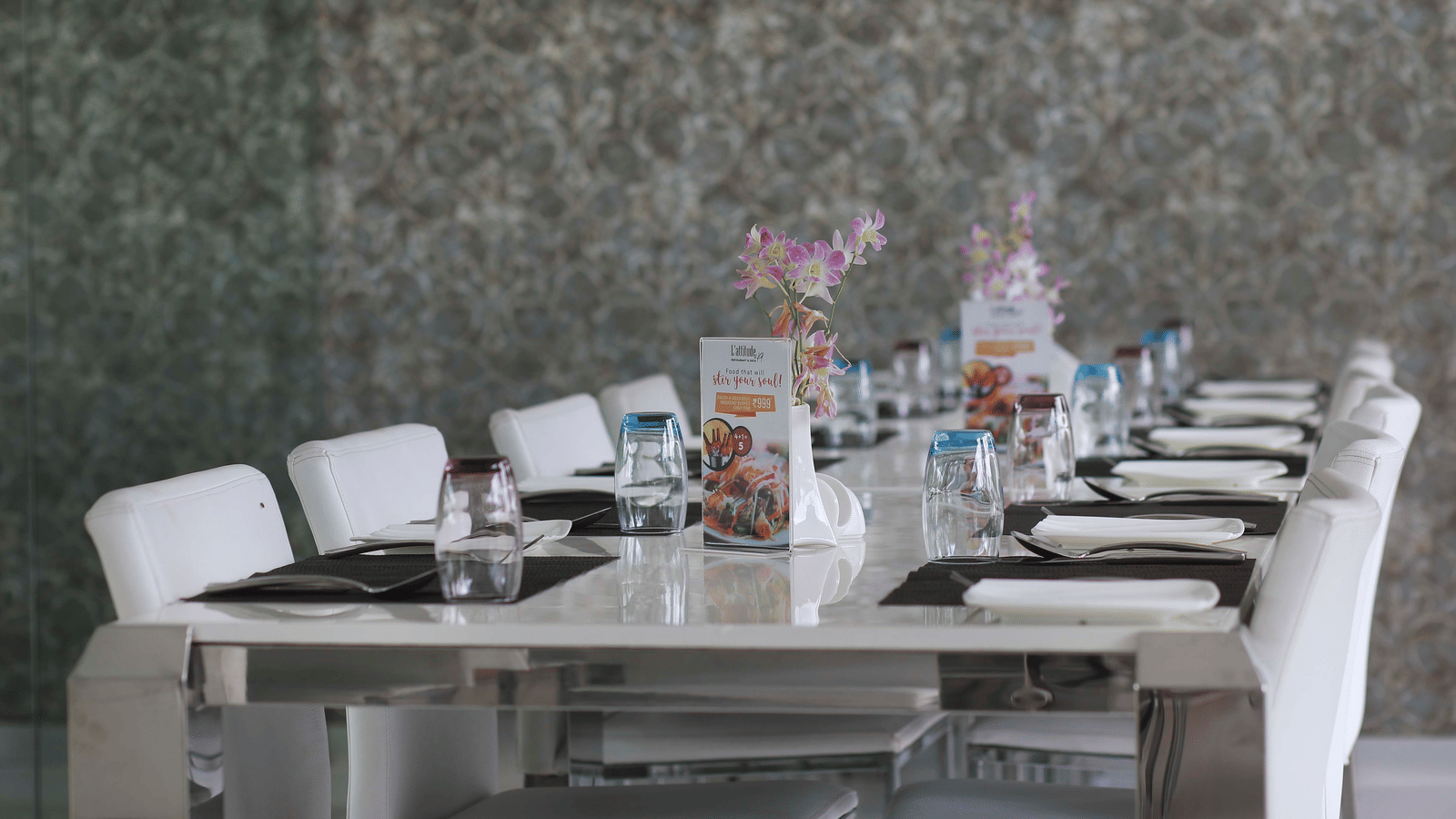 A long dining table set with white chairs, place settings, and colourful floral decorations - Grand Bay Resort & Spa - Grande Bay Resort & Spa, Mamallapuram