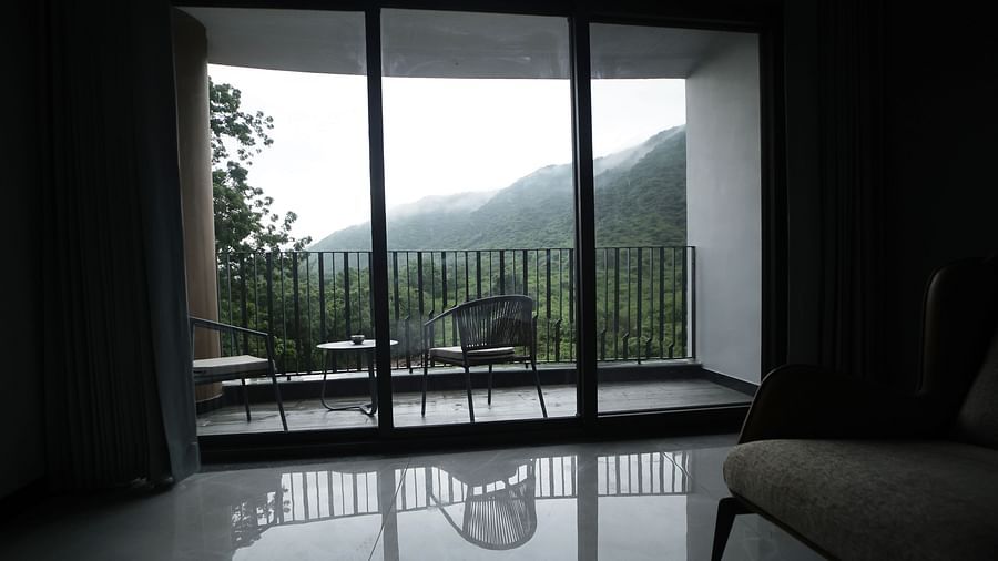 Club Suite with Valley View Sitout with sliding glass doors leading to a balcony overlooking a mountainous landscape at The Qualia Resort Club & Brewery, Udaipur.