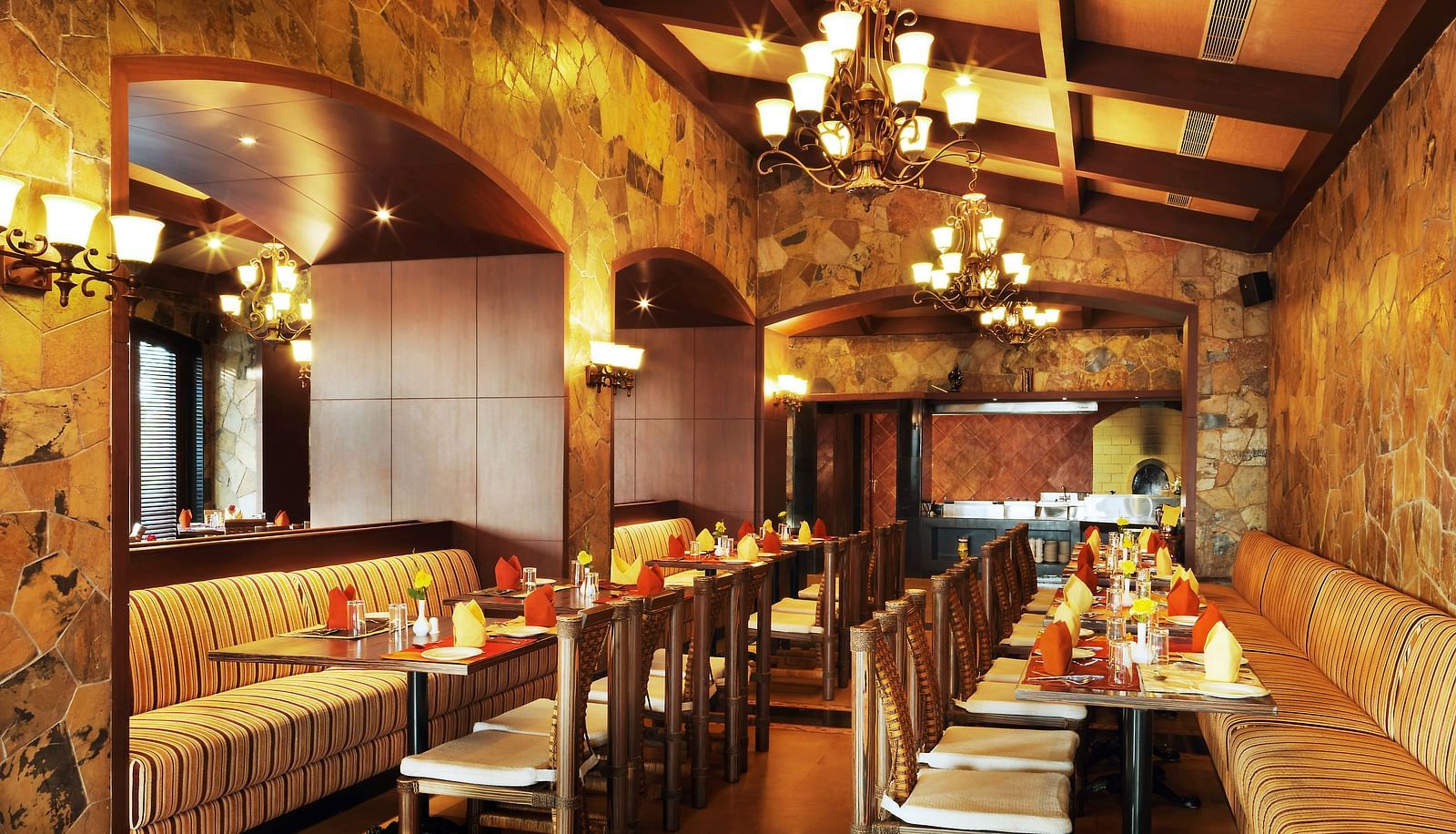 Amber restaurant at Ocean Spray Pondicherry featuring sofa, chairs, and a dining table in between where plates, cutlery, and hand towels are placed