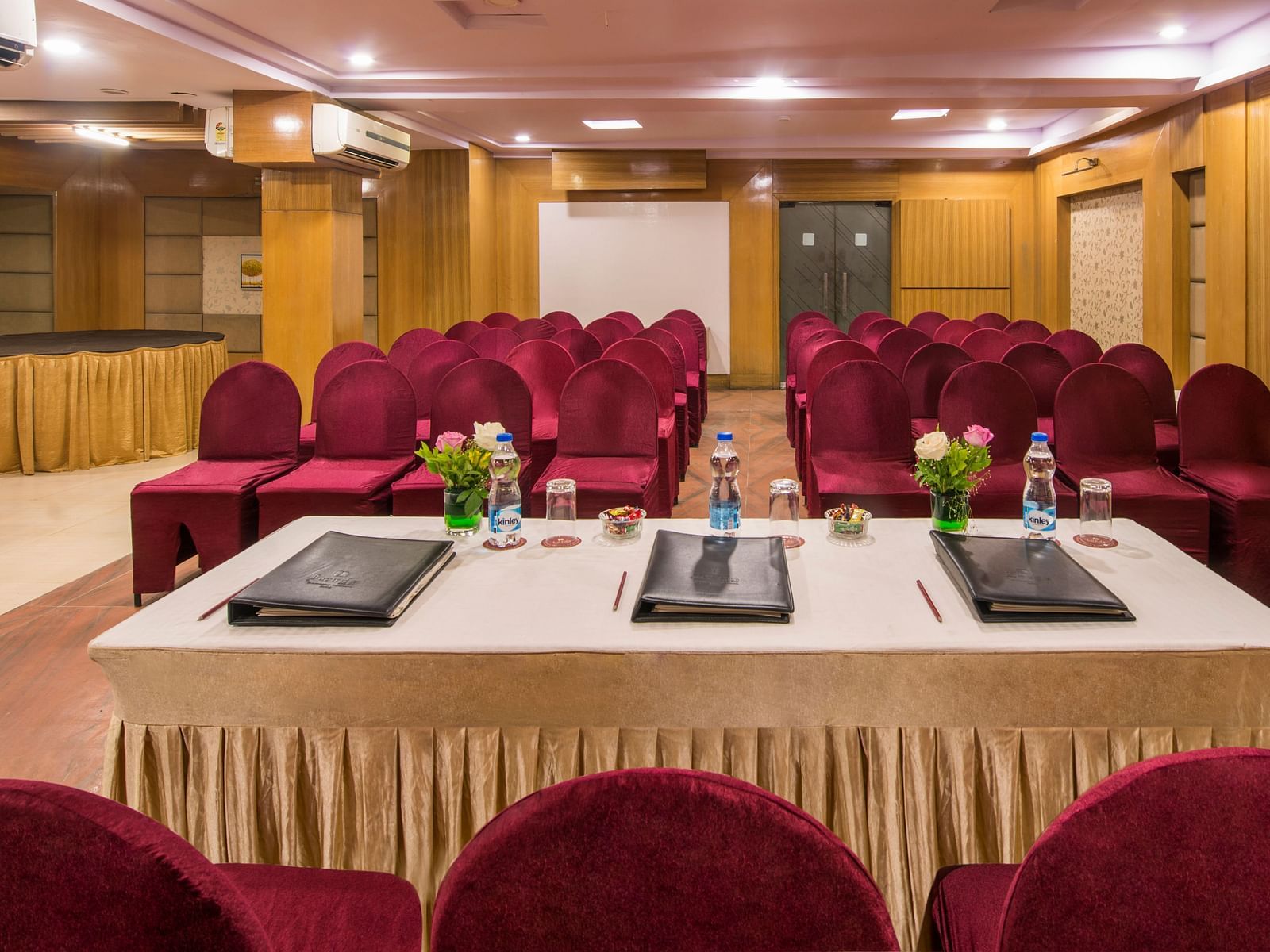 A meeting room with a white table, laptops, and red cushioned chairs - Lords Eco Inn Dahej