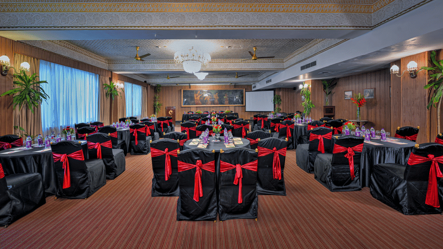 A hall at The Clarks Varanasi, with chairs, tables, and a chandelier.