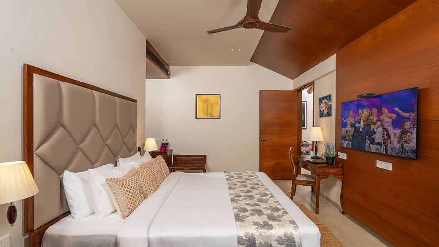 Bedroom of Premium Pool Villa at Uday Backwater Resort featuring a plush bed and a TV in front of it mounted on the wall and a work desk next to it