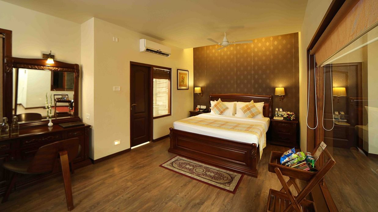 The Grand Family Suite at Uday Samudra Leisure Beach Hotel, Kovalam, features a bedroom with a king size bed, a desk, and a balcony.