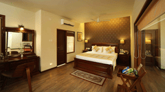 The Grand Family Suite at Uday Samudra Leisure Beach Hotel, Kovalam, features a bedroom with a king size bed, a desk, and a balcony.