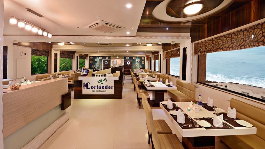 A well-lit restaurant dining area at Lords Inn Porbandar, features comfortable seating and views through large windows.