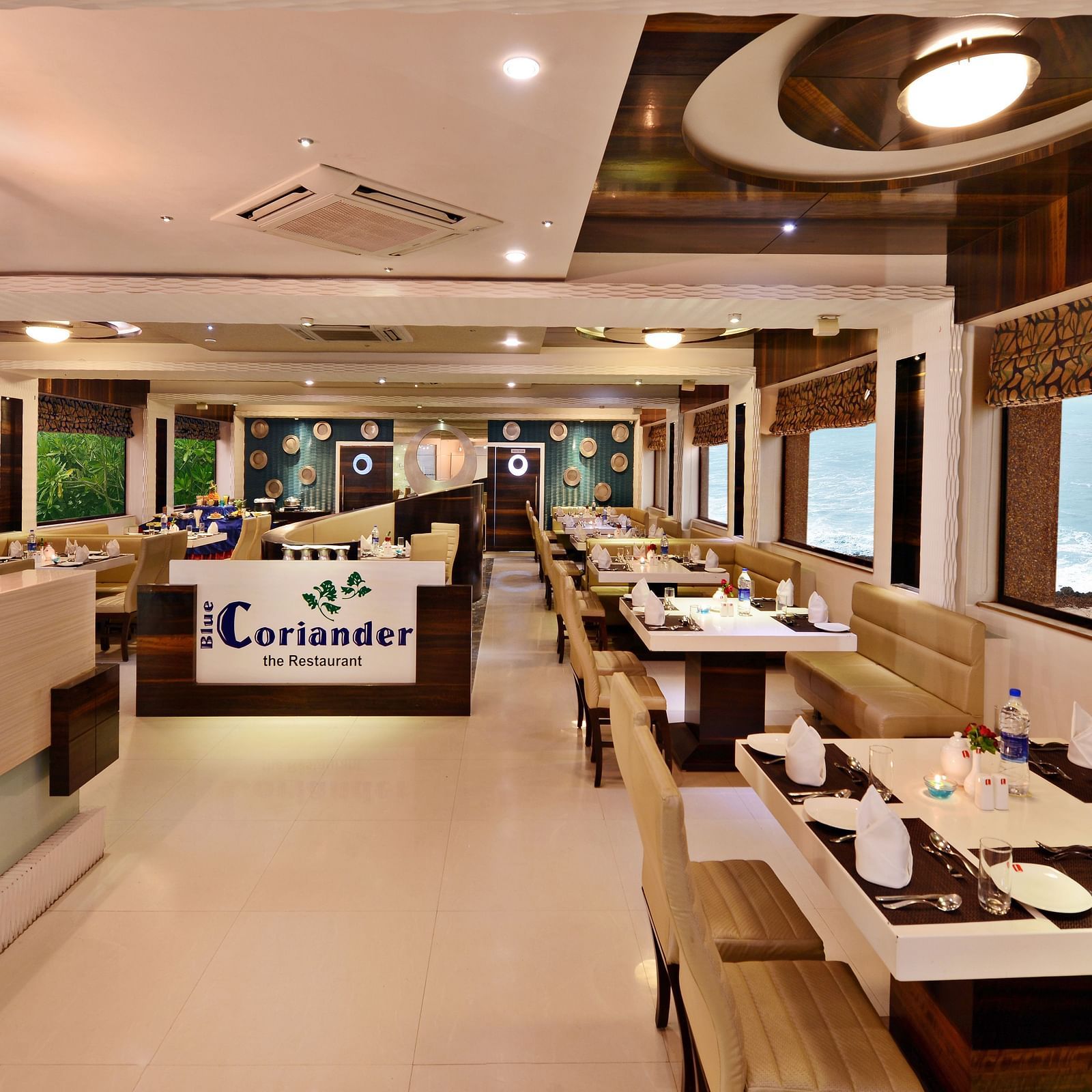 A well-lit restaurant dining area at Lords Inn Porbandar, features comfortable seating and views through large windows.