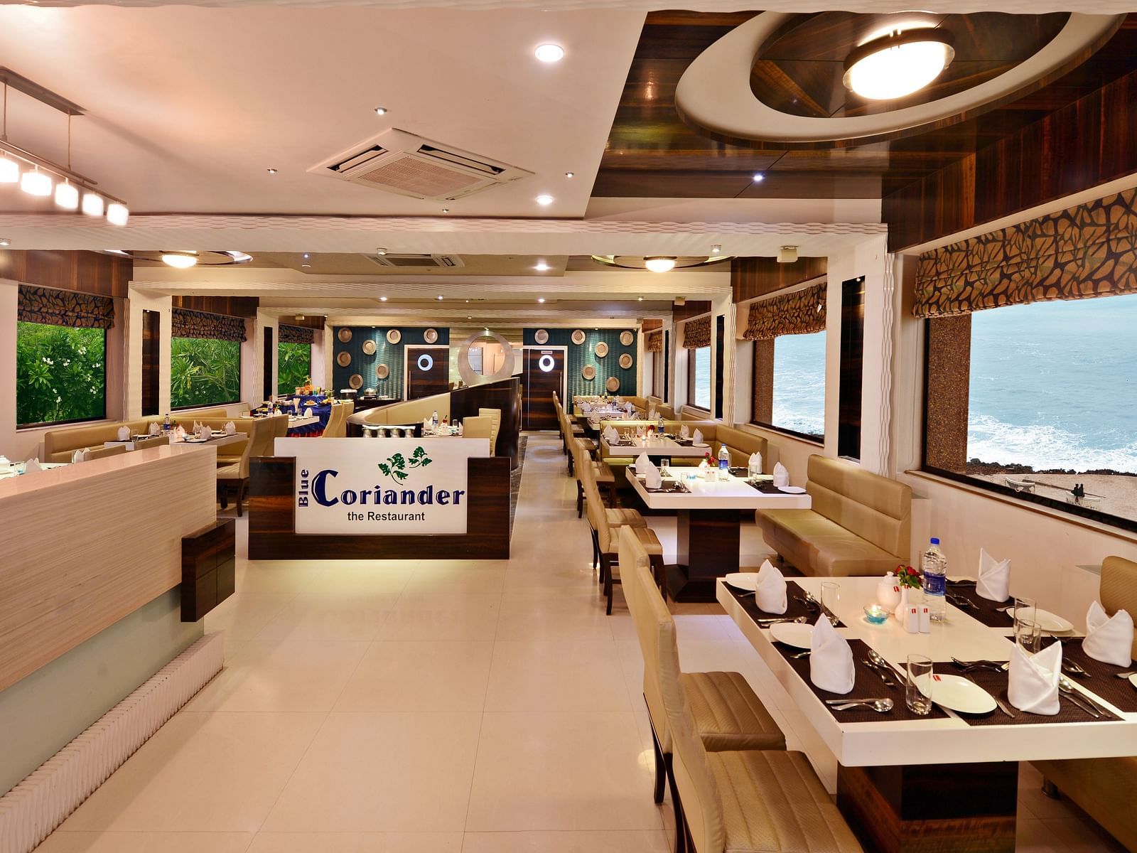 A well-lit restaurant dining area at Lords Inn Porbandar, features comfortable seating and views through large windows.
