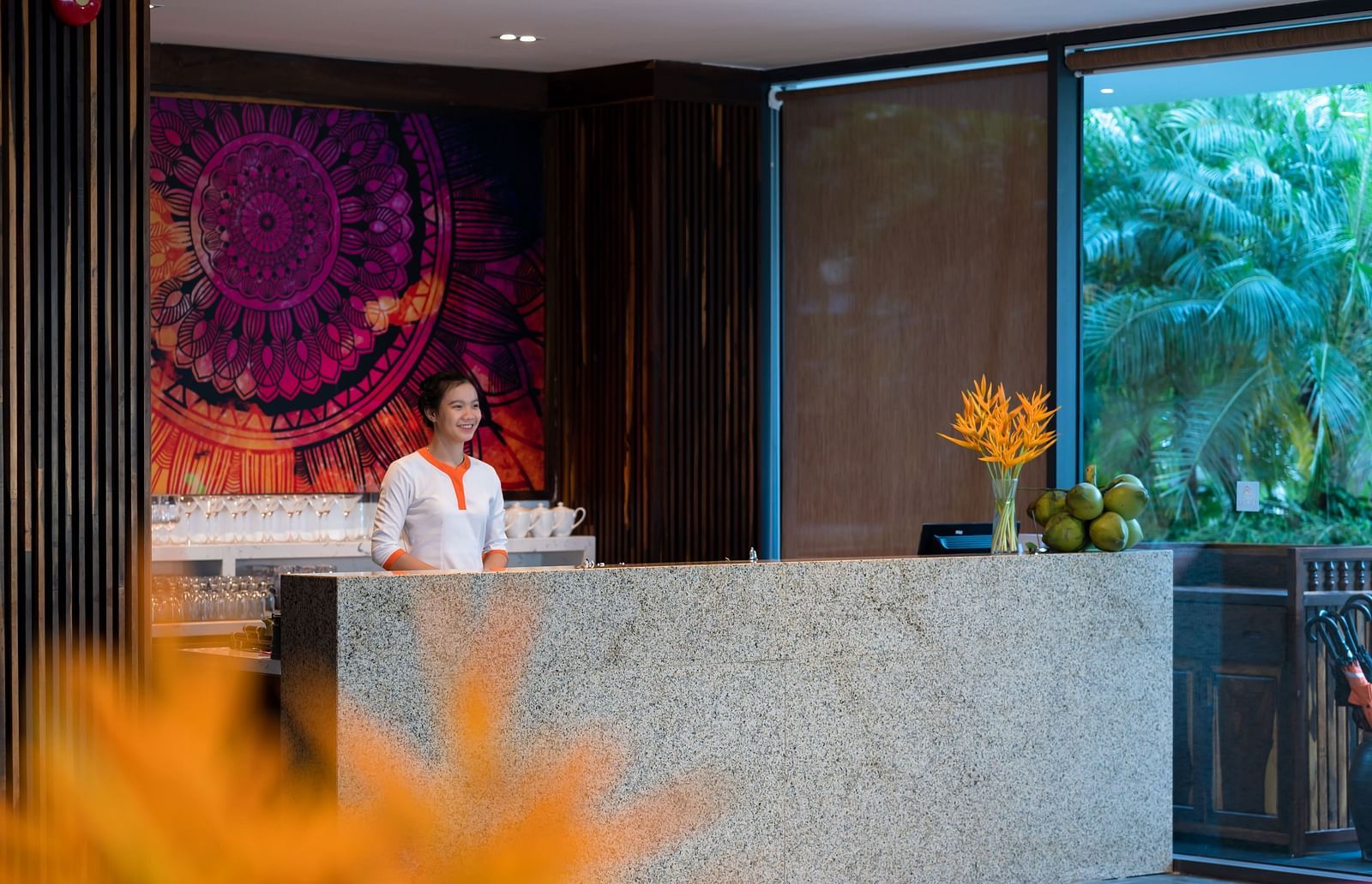 A reception desk with a receptionist standing in the background - Alibu Resort Nha Trang
