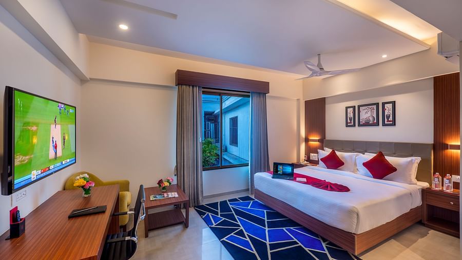 Stylish hotel room featuring a work desk, flat-screen TV, and balcony access - Lords Eco Inn Shapar Rajkot