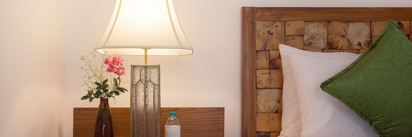 A side table besides a double bed in a room at Saraca Resort & Spa Corbett