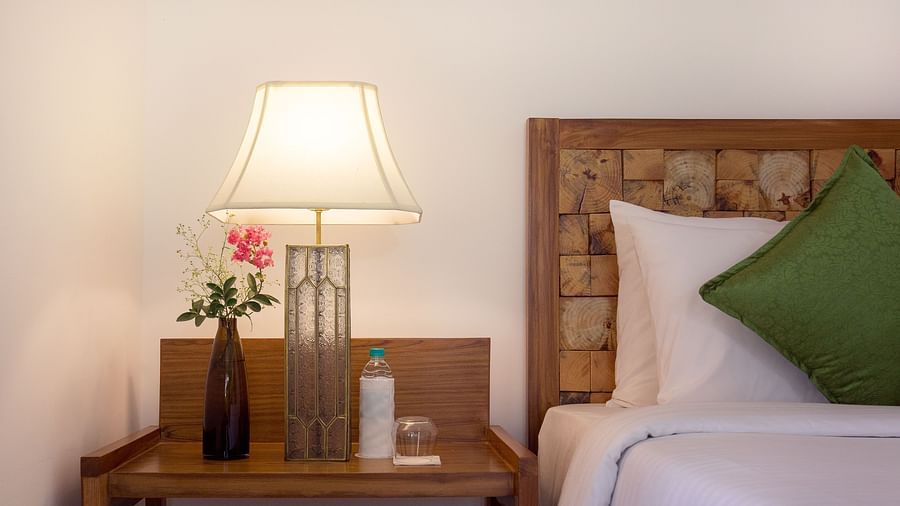 A side table besides a double bed in a room at Saraca Resort & Spa Corbett