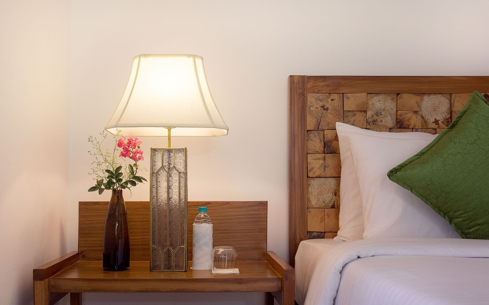 A side table besides a double bed in a room at Saraca Resort & Spa Corbett