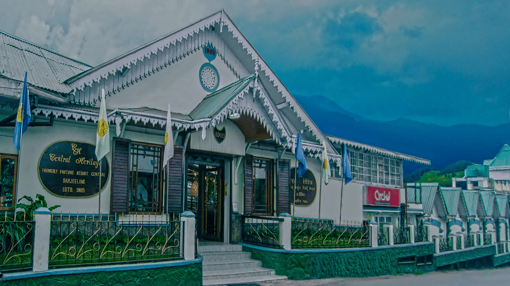 Facade of Central Heritage Resort and Spa with mountain shadows under a blue sky.