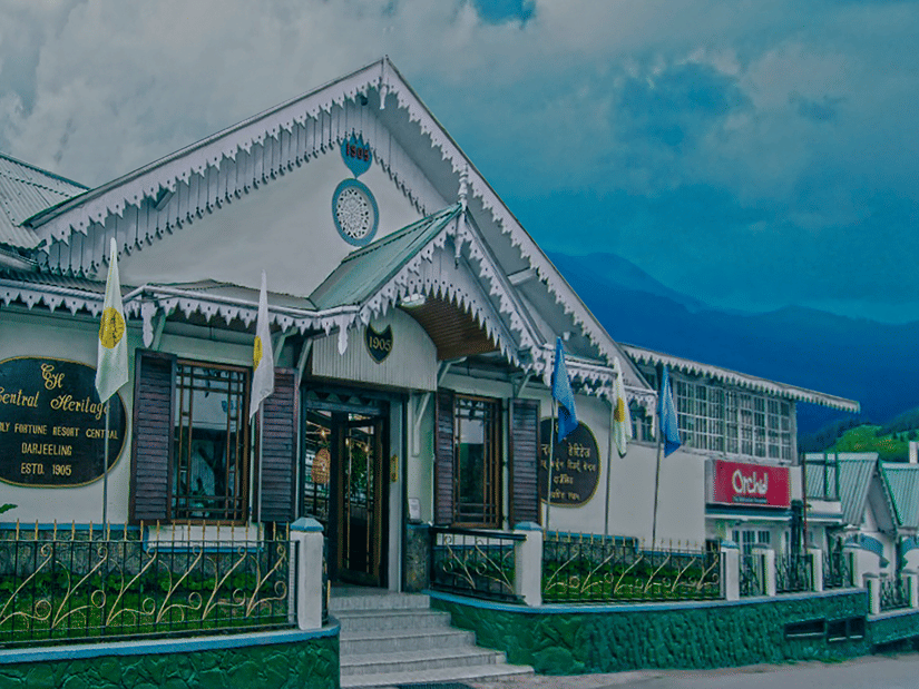 Facade of Central Heritage Resort and Spa with mountain shadows under a blue sky.