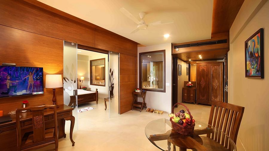 The Lake View Suite’s living room featuring a comfortable seating area facing a wall-mounted TV, with a work desk positioned below and the bedroom entrance located nearby