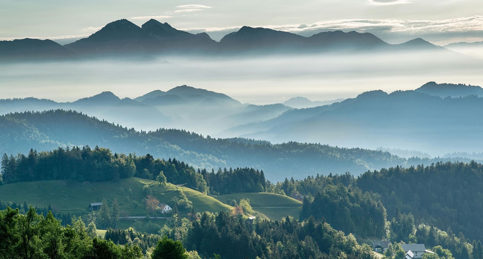 An image of hills with greenery and clouds hovering over