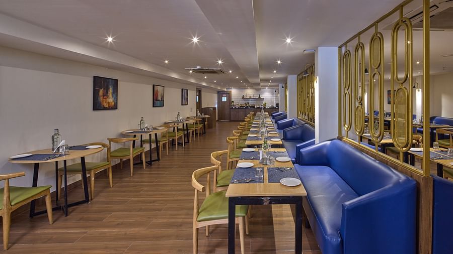 A dining area at our restaurant in Bengaluru with ambient lighting, cosy couches and upholstered chairs - Grand Continent, Brookefield