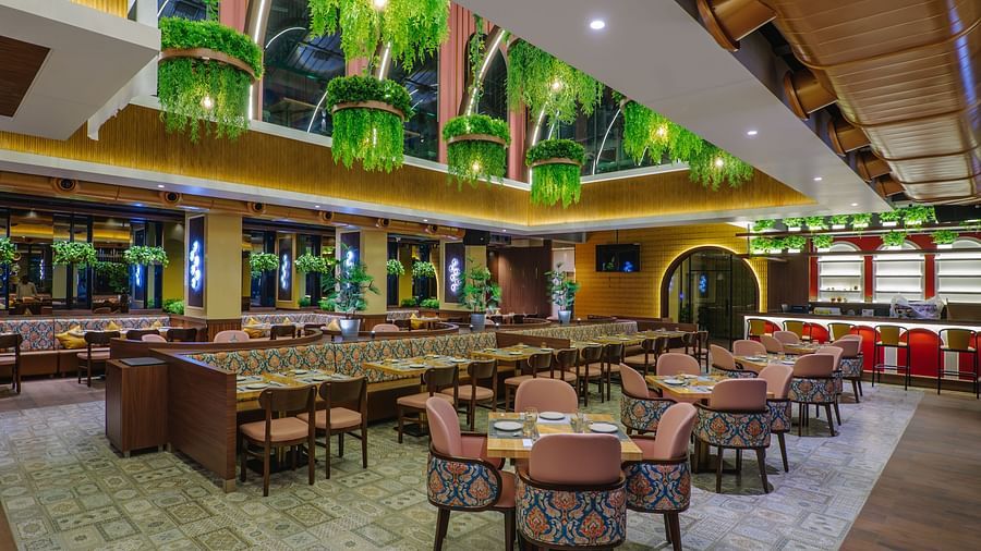 An elaborately decorated dining area with multiple tables and chairs, featuring ornate ceiling designs and warm lighting - Melior Inn