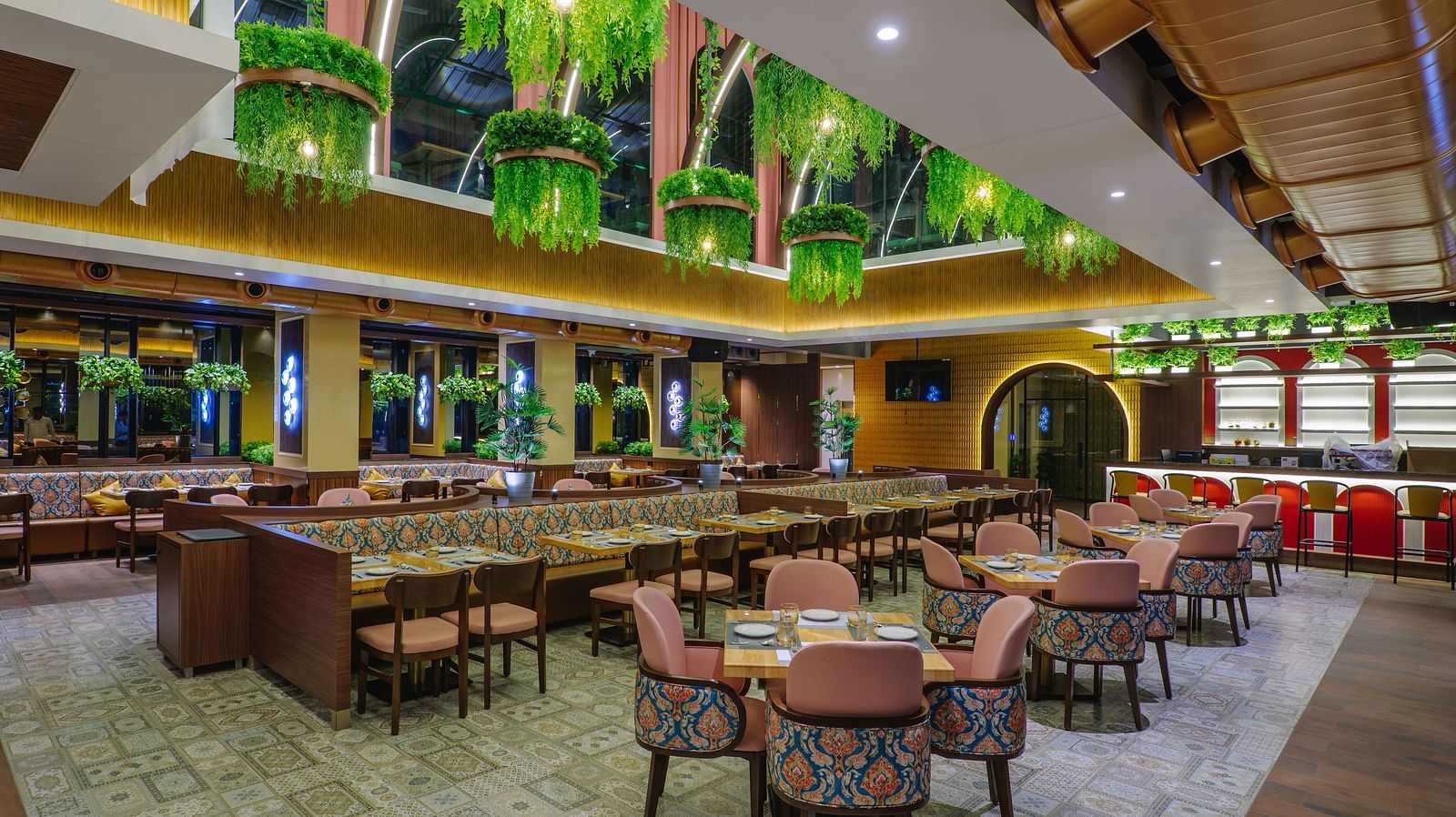 An elaborately decorated dining area with multiple tables and chairs, featuring ornate ceiling designs and warm lighting - Melior Inn