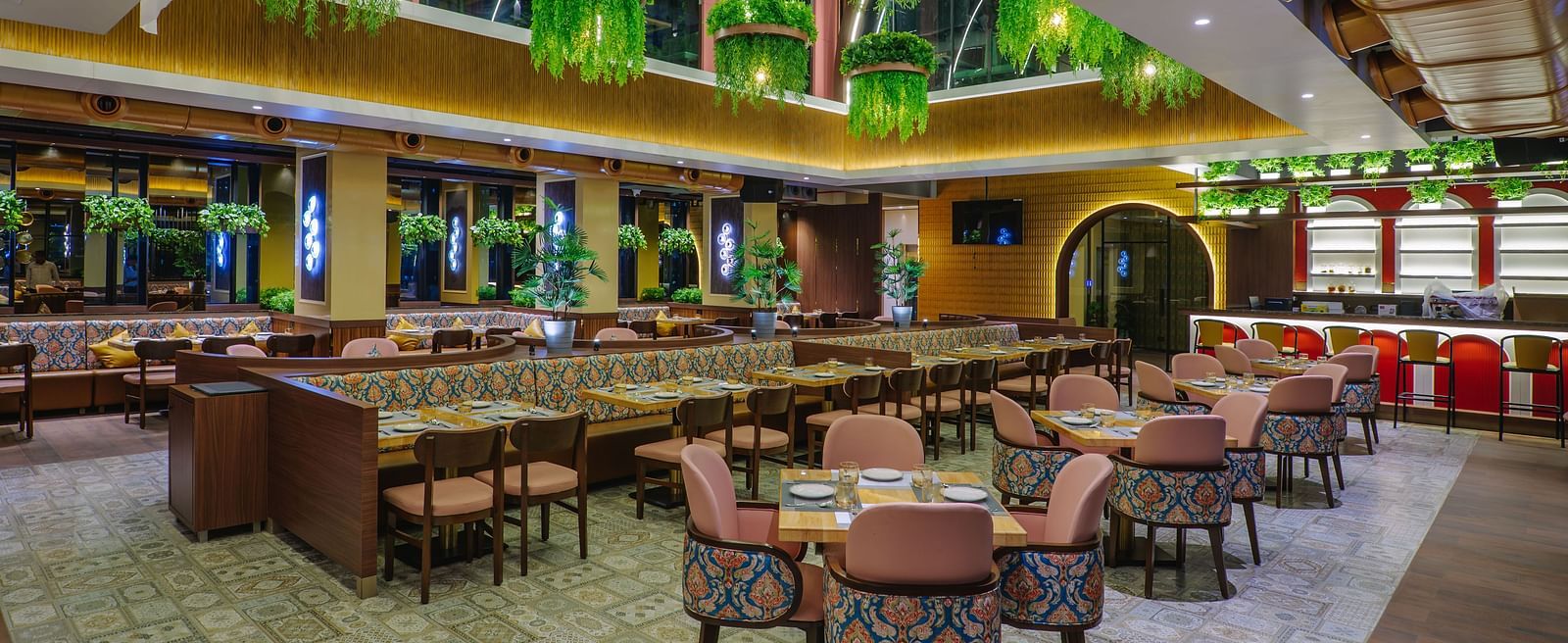 An elaborately decorated dining area with multiple tables and chairs, featuring ornate ceiling designs and warm lighting - Melior Inn