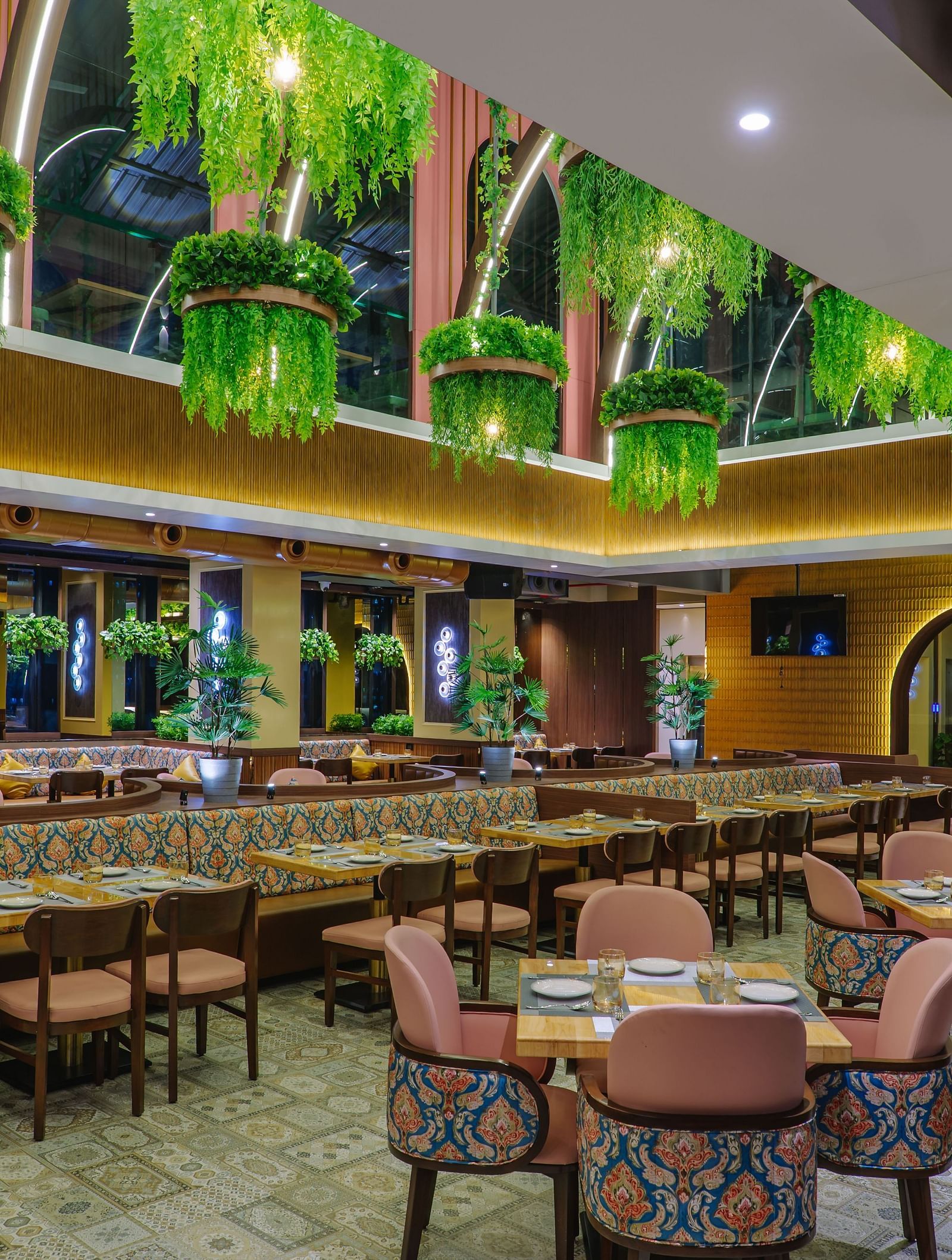 An elaborately decorated dining area with multiple tables and chairs, featuring ornate ceiling designs and warm lighting - Melior Inn
