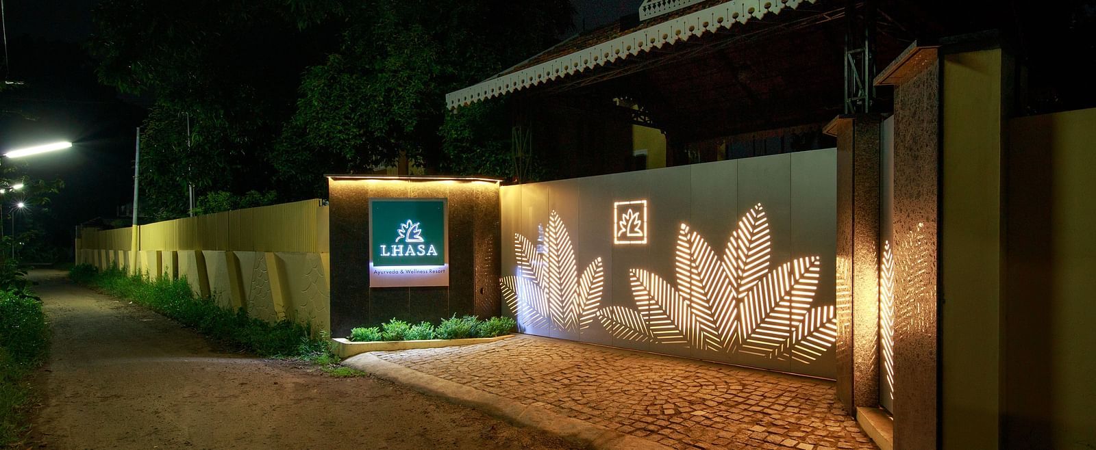 An outdoor view of a building at night with illuminated signage and a decorated wall.