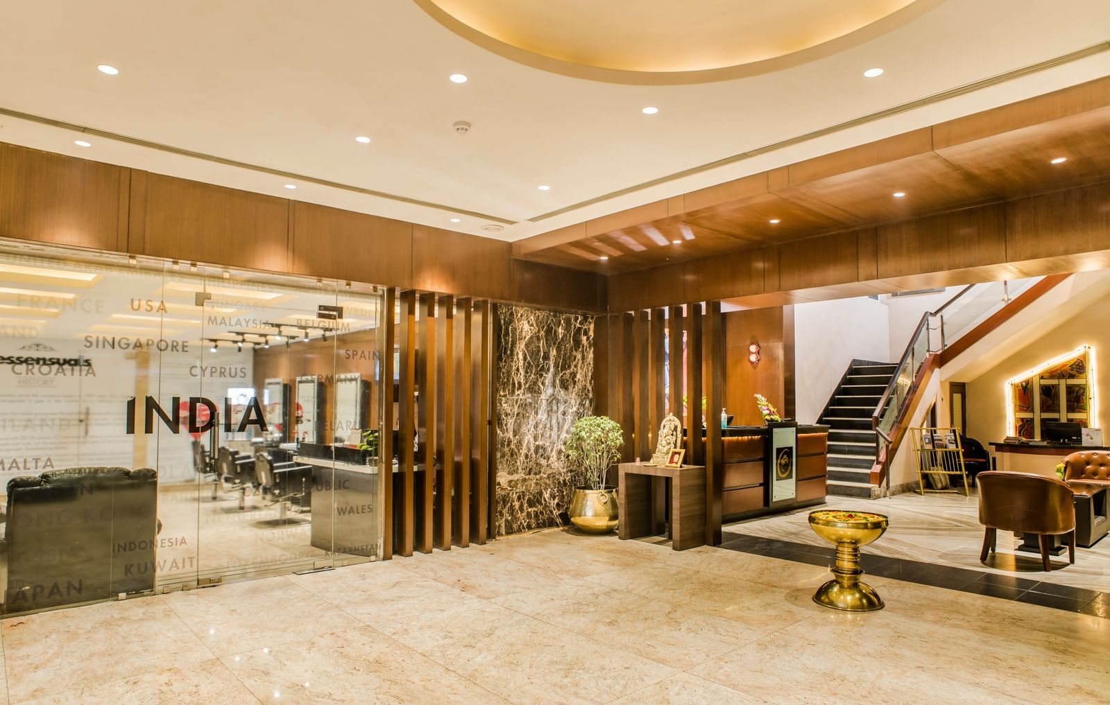 A brightly lit and modern hotel lobby entrance with wodden chairs and a reception desk at The Citi Residenci Hotel, Asansol
