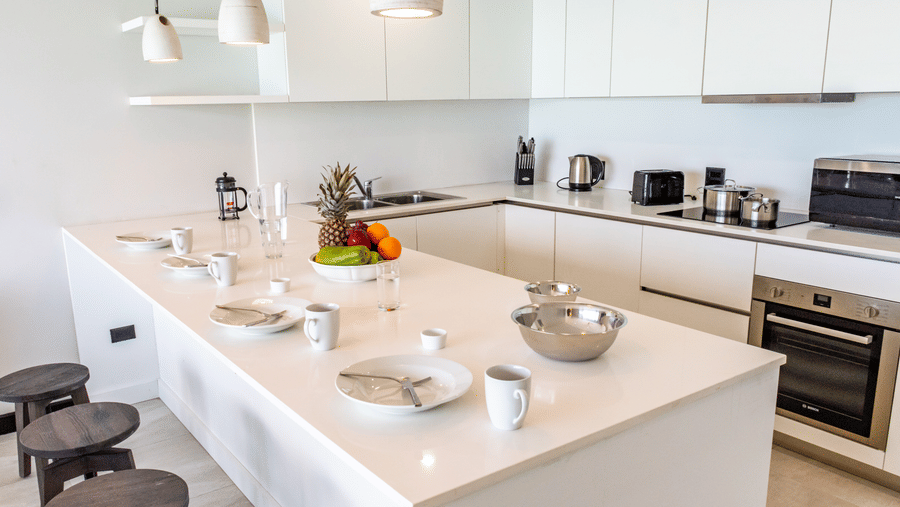 A kitchen at Tamarind Hills Resort and Villas, Antigua, with appliances, a kitchen island, a sink and stools.