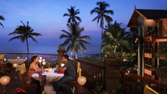 A couple enjoying candlelight dinner at Uday Samudra Leisure Beach Hotel amid ambient lighting with a backdrop of evening sky with different hues of blue