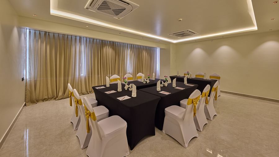 A banquet hall showcasing chairs in white fabric around a long table in navy blue cloths, lit by gentle lighting